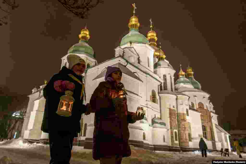 Дівчатка із «вифлеємським вогнем» біля Софійського собору у Києві. Україна. 10 грудня 2023 року