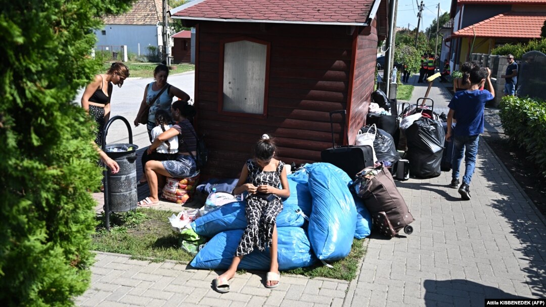 Ukrajinske izbeglice iz Zakarpatja sede na trotoaru blizu svog bivšeg skloništa u selu Koč, oko 70 km severozapadno od Budimpešte, 21. avgust 2024. 