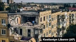 Чоловік розчищає зруйновану обстрілом квартиру в житловому будинку в Нікополі, 15 серпня 2022 року
