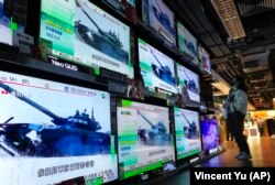 Гонконгте теледидардан Ресей әскерінің Украинаға басып кіргені туралы хабарды көріп тұрған әйел. 24 ақпан 2022 жыл.