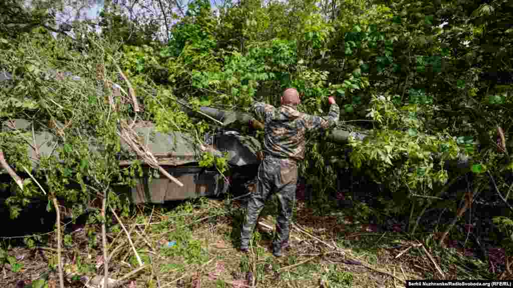 Український військовий маскує на позиціях захоплений у бою російський танк Т-80. Харківська область, 1 травня 2022 року 