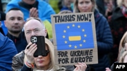 Участник демонстрации у Бранденбургских ворот в поддержку Украины держит плакат с надписью «Taurus now – for Ukraine, for Europe», 9 марта 2025 года, Берлин.