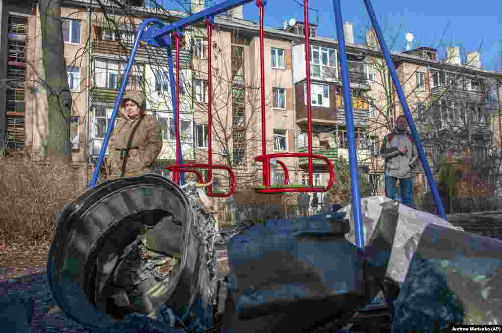 Пас аз ҳамлаи ҳавоии Русия дар Харков, як мард ва як зан дар паҳлӯи таҷҳизоти низомӣ истодаанд. &nbsp; &nbsp; 