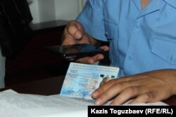 Прокурор Еркін Баймағамбетов өзінің ұялы телефонына америкалық адвокат Джаред Генсердің төлқұжатын суретке түсіріп отыр.
