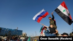Сирійці розмахують сирійськими і російськими прапорами, протестуючи проти ракетних ударів США і їхніх союзників, 14 квітня 2018 року
