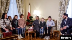 Катарські і російські представники поряд з українськими дітьми та членами їхніх сімей перед від’їздом в Україну у посольстві Катару в Москві, 5 грудня 2023 року