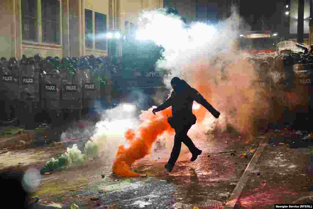 29 noyabr. Etirazların ikinci gecəsi maskalı polis tüstü bombasını təpikləyir.