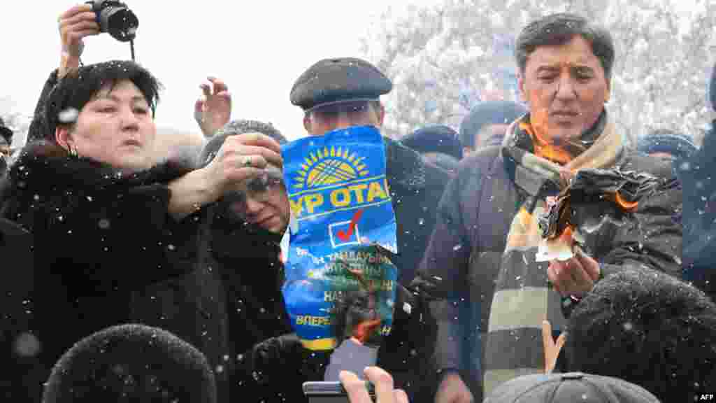Болат Әбілев (оң жақтан бірінші) оппозиция жетекшілерімен бірге парламент сайлауы нәтижесіне наразылық ретінде "Нұр Отан" партиясының плакатын өртеп тұр. Алматы, 17 қаңтар 2012 жыл.