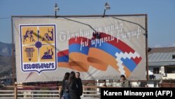 Nagorno Karabakh -- Pedestrians walk past a poster bearing a flag of Nagorno-Karabakh in Stepanakert on November 24, 2020, 