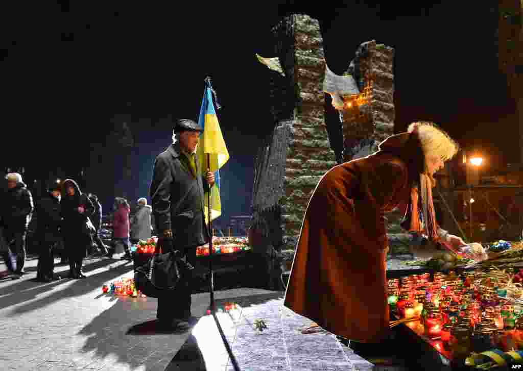 Жінка кладе шматок хліба до Меморіалу&nbsp;жертвам&nbsp;Голодомору у Києві. В суботу, 26 листопада, в Україні вшановують пам&rsquo;ять жертв голодоморів, в результаті яких загинули мільйони людей. Сьогодні в Україні приспущені державні прапори і скасовані розважальні заходи. Київ, 26 листопада 2016 року