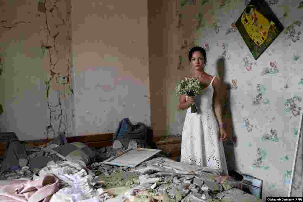 31-річна Дар&#39;я Стенюкова позує для весільних фотографій у своїй розбомбленій квартирі у Вінниці 16 липня. Напередодні весілля дівчини російські війська обстріляли ракетами центр міста, загинули 26 людей. Однак подружжя було налаштоване рішуче:&nbsp;&laquo;Мій будинок був зруйнований, але не наші життя, &ndash; сказала Дар&#39;я в коментарі AFP. &ndash; Це був зухвалий меседж усьому світу &ndash; підкреслення того, наскільки сильні українці. Ми готові одружитися, навіть якщо над нашими головами летять ракети&raquo;.