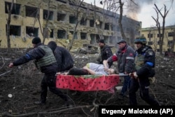 Українські рятувальники і волонтери несуть вагітну жінку Ірину Калініну, яка постраждала в результаті авіаційного удару російських військових по пологовому будинку та дитячій лікарні в Маріуполі, 9 березня 2022 року. Фото Євгена Малолєтки