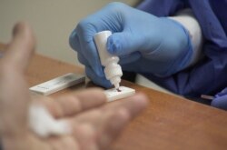 Медицинский работник берет кровь из пальца у пациента для выявления результатов экспресс-теста на коронавирус для местного водителя во Львове, Украина. 31 марта 2020 года.