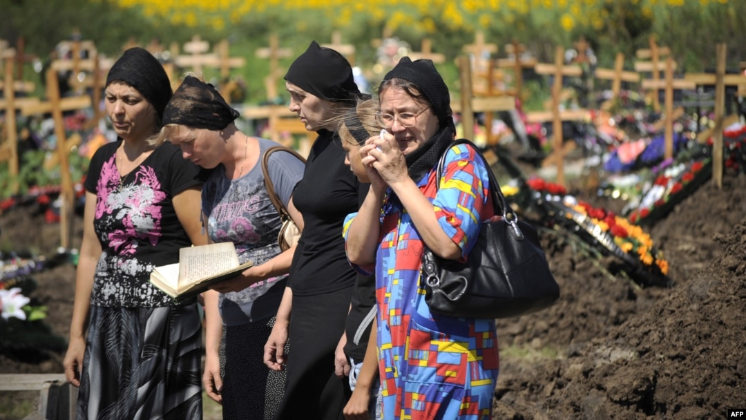 Relatives and friends of a flood victim mourn at his grave in a cemetery in the town of Krymsk in the southern Krasnodar region. 