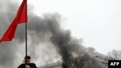 Сторонник оппозиции держит флаг Кыргызстана во время антиправительственного протеста. Бишкек, 7 апреля 2010 года.