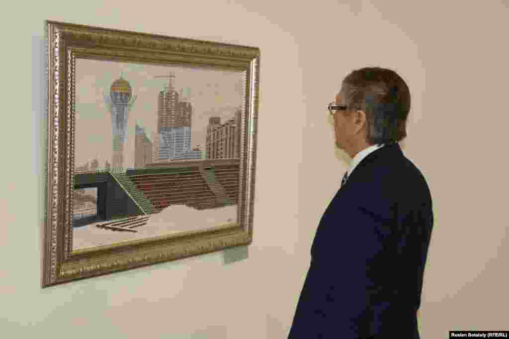 Суретші Қалиолла Ахметжанның «Арайлы Астана» туындысын қарап тұрған адам.