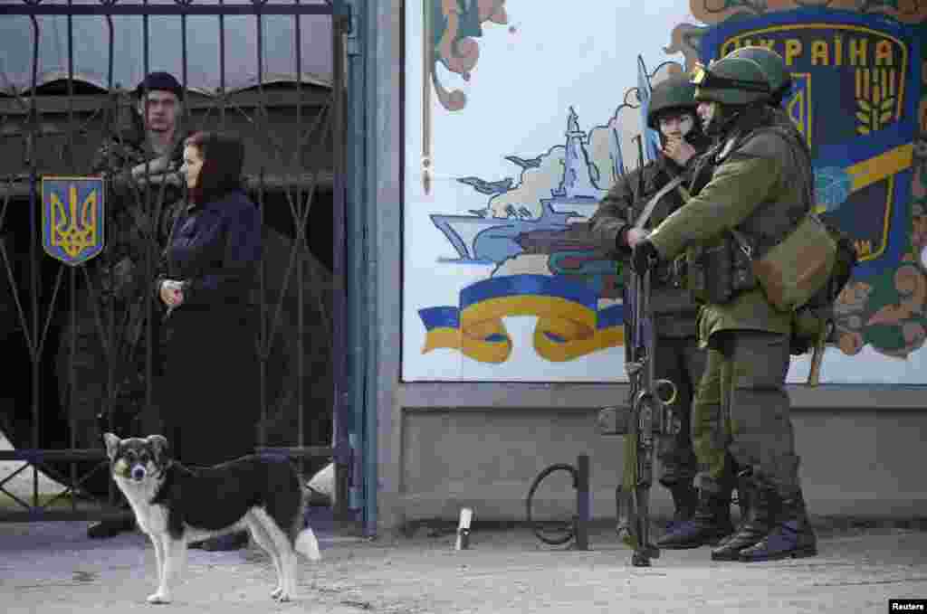 Военные рядом с КПП украинской военной базы. За забором видны украинские военнослужащие. 